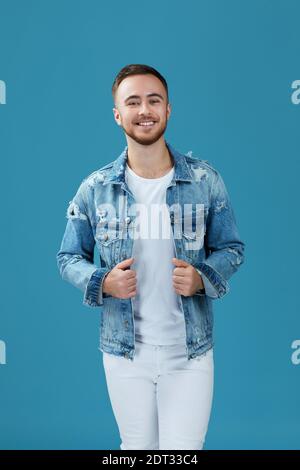 Gutaussehender lächelnder Mann in Denim, der die Kamera isoliert betrachtet Blauer Studiohintergrund Stockfoto