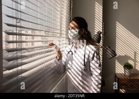 Ärztin in Gesichtsmaske Blick in der Ferne träumen Stockfoto