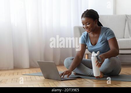 Junge Schwarze Frau Wahl Online-Tutorials Auf Laptop Für Die Ausbildung Zu Hause Stockfoto