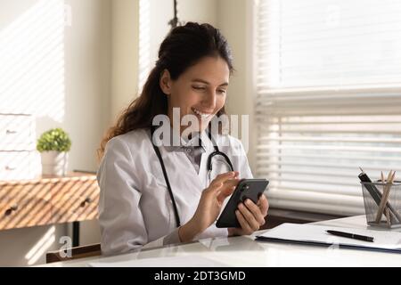 Lächelnde Ärztin benutzen Smartphone im Krankenhaus Stockfoto
