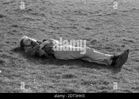 Großbritannien, England, Devonshire, Buckfastleigh, 1972. Punkt-zu-Punkt-Rennen wurden am Dean Court auf den Dean Marshes, in der Nähe der A38 zwischen Plymouth und Exeter, abgehalten. Ein junger Mann, der sich auf dem Feld zur Ruhe legt. Stockfoto