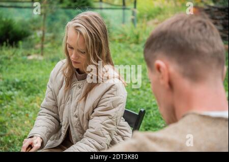 Junge Papa und Mama schneiden Gemüse und bereiten sich darauf vor Ein Familienpicknick im Innenhof des eigenen Landes Haus Stockfoto