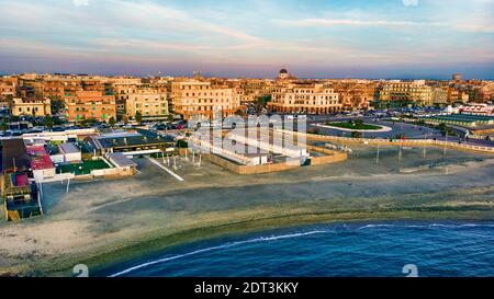 Sonnenuntergang Rom Luftaufnahme in Ostia Lido Strand über blau Satinmeer mit Skyline der Stadt und Blick auf den Ravennati Platz Und Blick auf Fußgängerpier eine Landma Stockfoto