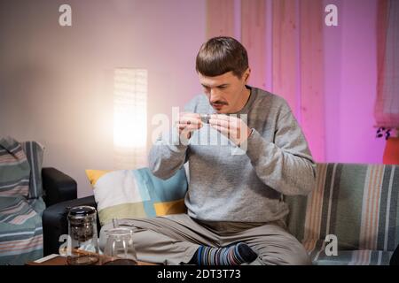 Ein junger Mann trinkt köstlichen, aromatischen schwarzen chinesischen Tee aus einer Glasschüssel während einer authentischen Teezeremonie zu Hause Stockfoto