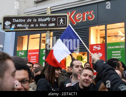 Fans des französischen Comics Dieudonne M'Bala M'Bala treffen sich in der Nähe eines Pariser Theaters, als einer von ihnen am 11. Januar 2014 in Paris die französische Nationalflagge schwingt und eine Ananas hält. Dieudonne wurde wiederholt wegen Anstiftung zu Rassenhass oder Antisemitismus verurteilt und hat zugestimmt, eine umstrittene Show aufzugeben, die in mehreren Städten verboten wurde. Nachdem eine Pariser Show heute von den Behörden verboten wurde, sagte er einer Pressekonferenz, dass er die "Le Mur" Show nicht mehr machen werde, sondern sie durch eine neue Performance ersetzen werde. Der Comic wurde im vergangenen Herbst für die Verwendung des Wortes "Shoanana verurteilt Stockfoto