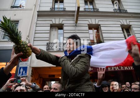 Fans des französischen Comics Dieudonne M'Bala M'Bala treffen sich in der Nähe eines Pariser Theaters, als einer von ihnen am 11. Januar 2014 in Paris die französische Nationalflagge schwingt und eine Ananas hält. Dieudonne wurde wiederholt wegen Anstiftung zu Rassenhass oder Antisemitismus verurteilt und hat zugestimmt, eine umstrittene Show aufzugeben, die in mehreren Städten verboten wurde. Nachdem eine Pariser Show heute von den Behörden verboten wurde, sagte er einer Pressekonferenz, dass er die "Le Mur" Show nicht mehr machen werde, sondern sie durch eine neue Performance ersetzen werde. Der Comic wurde im vergangenen Herbst für die Verwendung des Wortes "Shoanana verurteilt Stockfoto