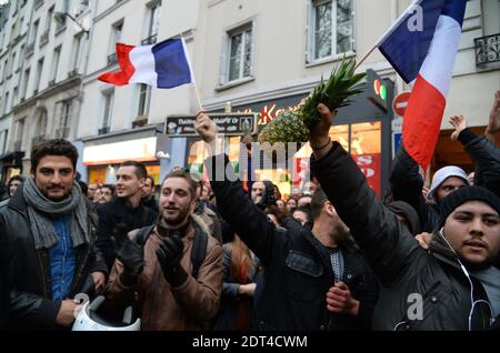 Fans des französischen Comics Dieudonne M'Bala M'Bala treffen sich in der Nähe eines Pariser Theaters, als einer von ihnen am 11. Januar 2014 in Paris die französische Nationalflagge schwingt und eine Ananas hält. Dieudonne wurde wiederholt wegen Anstiftung zu Rassenhass oder Antisemitismus verurteilt und hat zugestimmt, eine umstrittene Show aufzugeben, die in mehreren Städten verboten wurde. Nachdem eine Pariser Show heute von den Behörden verboten wurde, sagte er einer Pressekonferenz, dass er die "Le Mur" Show nicht mehr machen werde, sondern sie durch eine neue Performance ersetzen werde. Der Comic wurde im vergangenen Herbst für die Verwendung des Wortes "Shoanana verurteilt Stockfoto