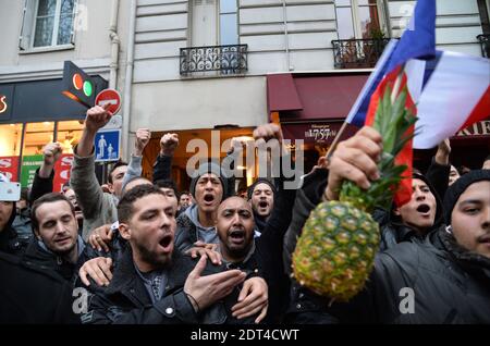 Fans des französischen Comics Dieudonne M'Bala M'Bala treffen sich in der Nähe eines Pariser Theaters, als einer von ihnen am 11. Januar 2014 in Paris die französische Nationalflagge schwingt und eine Ananas hält. Dieudonne wurde wiederholt wegen Anstiftung zu Rassenhass oder Antisemitismus verurteilt und hat zugestimmt, eine umstrittene Show aufzugeben, die in mehreren Städten verboten wurde. Nachdem eine Pariser Show heute von den Behörden verboten wurde, sagte er einer Pressekonferenz, dass er die "Le Mur" Show nicht mehr machen werde, sondern sie durch eine neue Performance ersetzen werde. Der Comic wurde im vergangenen Herbst für die Verwendung des Wortes "Shoanana verurteilt Stockfoto