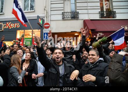 Fans des französischen Comics Dieudonne M'Bala M'Bala treffen sich in der Nähe eines Pariser Theaters, als einer von ihnen am 11. Januar 2014 in Paris die französische Nationalflagge schwingt und eine Ananas hält. Dieudonne wurde wiederholt wegen Anstiftung zu Rassenhass oder Antisemitismus verurteilt und hat zugestimmt, eine umstrittene Show aufzugeben, die in mehreren Städten verboten wurde. Nachdem eine Pariser Show heute von den Behörden verboten wurde, sagte er einer Pressekonferenz, dass er die "Le Mur" Show nicht mehr machen werde, sondern sie durch eine neue Performance ersetzen werde. Der Comic wurde im vergangenen Herbst für die Verwendung des Wortes "Shoanana verurteilt Stockfoto