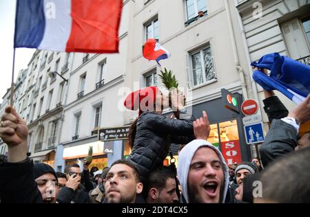 Fans des französischen Comics Dieudonne M'Bala M'Bala treffen sich in der Nähe eines Pariser Theaters, als einer von ihnen am 11. Januar 2014 in Paris die französische Nationalflagge schwingt und eine Ananas hält. Dieudonne wurde wiederholt wegen Anstiftung zu Rassenhass oder Antisemitismus verurteilt und hat zugestimmt, eine umstrittene Show aufzugeben, die in mehreren Städten verboten wurde. Nachdem eine Pariser Show heute von den Behörden verboten wurde, sagte er einer Pressekonferenz, dass er die "Le Mur" Show nicht mehr machen werde, sondern sie durch eine neue Performance ersetzen werde. Der Comic wurde im vergangenen Herbst für die Verwendung des Wortes "Shoanana verurteilt Stockfoto