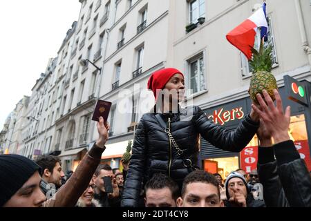 Fans des französischen Comics Dieudonne M'Bala M'Bala treffen sich in der Nähe eines Pariser Theaters, als einer von ihnen am 11. Januar 2014 in Paris die französische Nationalflagge schwingt und eine Ananas hält. Dieudonne wurde wiederholt wegen Anstiftung zu Rassenhass oder Antisemitismus verurteilt und hat zugestimmt, eine umstrittene Show aufzugeben, die in mehreren Städten verboten wurde. Nachdem eine Pariser Show heute von den Behörden verboten wurde, sagte er einer Pressekonferenz, dass er die "Le Mur" Show nicht mehr machen werde, sondern sie durch eine neue Performance ersetzen werde. Der Comic wurde im vergangenen Herbst für die Verwendung des Wortes "Shoanana verurteilt Stockfoto