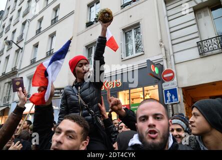 Fans des französischen Comics Dieudonne M'Bala M'Bala treffen sich in der Nähe eines Pariser Theaters, als einer von ihnen am 11. Januar 2014 in Paris die französische Nationalflagge schwingt und eine Ananas hält. Dieudonne wurde wiederholt wegen Anstiftung zu Rassenhass oder Antisemitismus verurteilt und hat zugestimmt, eine umstrittene Show aufzugeben, die in mehreren Städten verboten wurde. Nachdem eine Pariser Show heute von den Behörden verboten wurde, sagte er einer Pressekonferenz, dass er die "Le Mur" Show nicht mehr machen werde, sondern sie durch eine neue Performance ersetzen werde. Der Comic wurde im vergangenen Herbst für die Verwendung des Wortes "Shoanana verurteilt Stockfoto