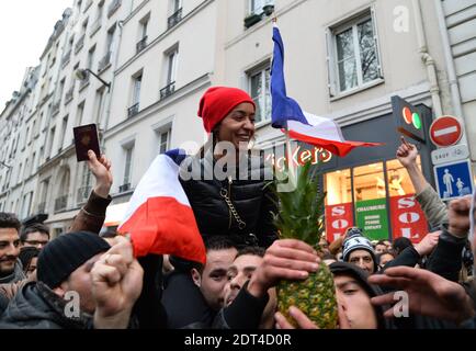 Fans des französischen Comics Dieudonne M'Bala M'Bala treffen sich in der Nähe eines Pariser Theaters, als einer von ihnen am 11. Januar 2014 in Paris die französische Nationalflagge schwingt und eine Ananas hält. Dieudonne wurde wiederholt wegen Anstiftung zu Rassenhass oder Antisemitismus verurteilt und hat zugestimmt, eine umstrittene Show aufzugeben, die in mehreren Städten verboten wurde. Nachdem eine Pariser Show heute von den Behörden verboten wurde, sagte er einer Pressekonferenz, dass er die "Le Mur" Show nicht mehr machen werde, sondern sie durch eine neue Performance ersetzen werde. Der Comic wurde im vergangenen Herbst für die Verwendung des Wortes "Shoanana verurteilt Stockfoto