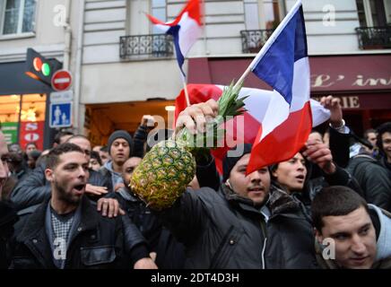 Fans des französischen Comics Dieudonne M'Bala M'Bala treffen sich in der Nähe eines Pariser Theaters, als einer von ihnen am 11. Januar 2014 in Paris die französische Nationalflagge schwingt und eine Ananas hält. Dieudonne wurde wiederholt wegen Anstiftung zu Rassenhass oder Antisemitismus verurteilt und hat zugestimmt, eine umstrittene Show aufzugeben, die in mehreren Städten verboten wurde. Nachdem eine Pariser Show heute von den Behörden verboten wurde, sagte er einer Pressekonferenz, dass er die "Le Mur" Show nicht mehr machen werde, sondern sie durch eine neue Performance ersetzen werde. Der Comic wurde im vergangenen Herbst für die Verwendung des Wortes "Shoanana verurteilt Stockfoto