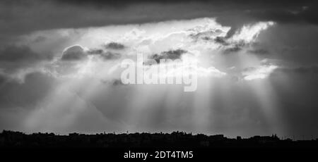 Dramatischer Himmel mit Sonnenstrahlen, die durch Wolken platzen Stockfoto