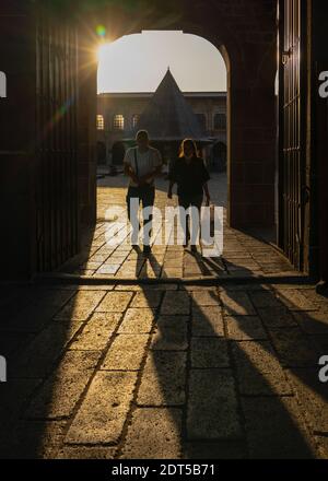 Sur, Diyarbakir, Türkei - September 17 2020: Die Menschen gehen unter die Tür der Ulu-Moschee mit ihrem Schatten und der Moschee im Hintergrund. Stockfoto