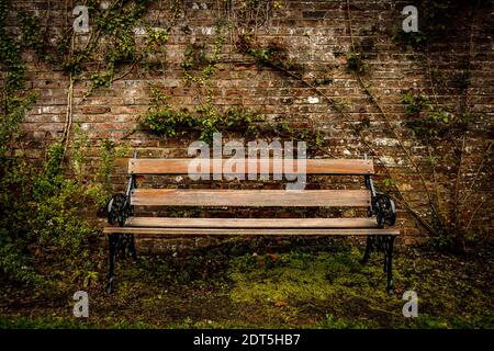 Holzbank im alten Stil und rote Ziegelwand im parken Stockfoto