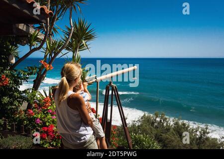 Mutter mit Sohn, der durch das Teleskop auf das Meer schaut Stockfoto