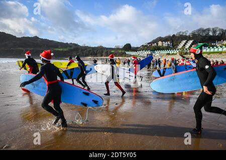 Swansea, Wales, Samstag, 19. Dezember 2020. Lokale Surfer Rennen in Richtung Meer während der Surf Santas Veranstaltung im Meer in Langland Bay auf Gower, Swansea, um Geld für Surfer gegen Kanalisation zu sammeln. Kredit: Robert Melen. Stockfoto