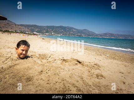 Porträt des Jungen im Sand am Strand begraben Stockfoto
