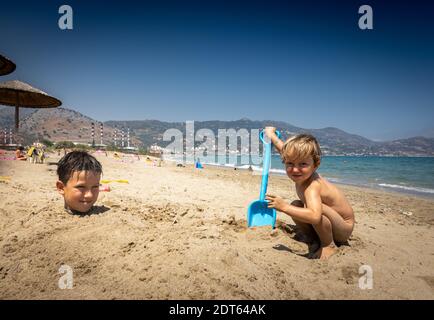 Brüder spielen im Sand am Strand Stockfoto