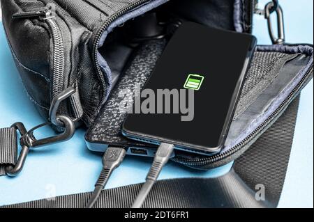 Nahaufnahme des Ladevorgangs eines Smartphones von einer Powerbank. Das Telefon und die Powerbank befinden sich in einer offenen Tasche. Stockfoto