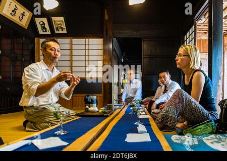 Kiyomi Uchino spricht mit erhobenen Händen zu seinen Gästen während der Teezeremonie im Uchino-Haus in der Nähe von Shizuoka, Japan. Stockfoto