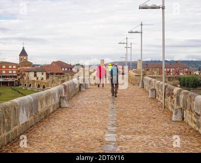 Pilger wandern auf der mittelalterlichen Brücke aus dem 13. Jahrhundert über den Fluss Orbigo - Hospital de Orbigo, Kastilien und Leon, Spanien Stockfoto