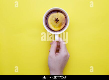 Weibliche Hand hält eine Tasse Obst Winter Tee mit Zitrone und Anis Stockfoto