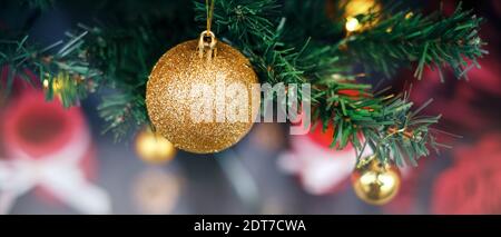 Magische Weihnachten - Weihnachtsbaum aus der Nähe, grüne Kiefernzweige mit glänzenden, traditionellen Gold- und roten Ornamenten. Für ein Website-Banner, Header, Schieberegler. Stockfoto