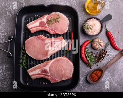 Frisches rohes Fleisch Schweinefleisch, Rindfleisch, auf Knochen hacken, auf Grillpfanne, Gewürze Stockfoto