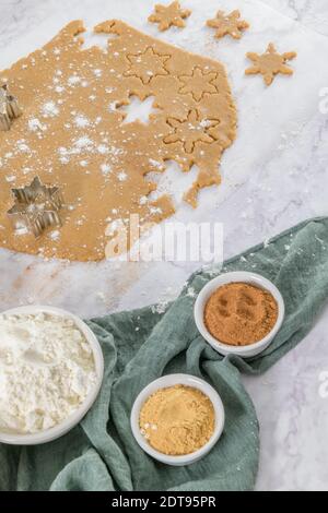 Roher Teig für weihnachtsplätzchen und Ausstechformen auf Küchenarbeitsplätzchen aus Marmor. Stockfoto