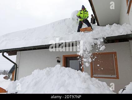 Zwei Männer schaufeln hohen schweren Schnee von einem Hausdach Stockfoto