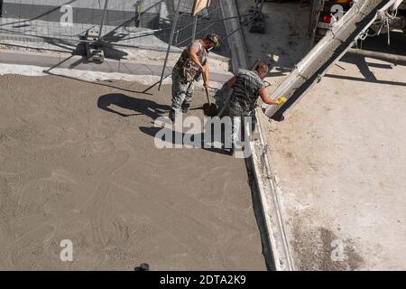 Zwei Männer legen Beton auf den Bürgersteig. Renovierungsarbeiten. Stockfoto