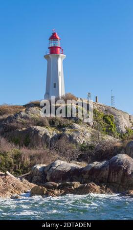 Wunderschöner Leuchtturm am felsigen Ufer und Wellen vom Meer. West Vancouver, British Columbia, Kanada - November 7,2020. Selektiver Fokus, Reisen Stockfoto