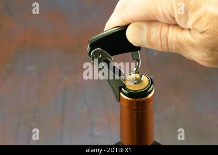 Eine Hand, die einen Korkenzieher aus seinem grünen Glas zieht Flasche und kupferfarbenen Hals Stockfoto