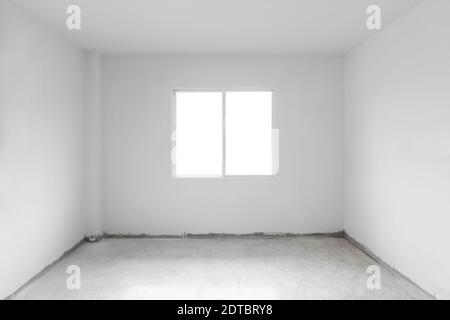 Betonzementboden mit weißer Wand und Fenster. Im Bau leeres Zimmer innen Stockfoto