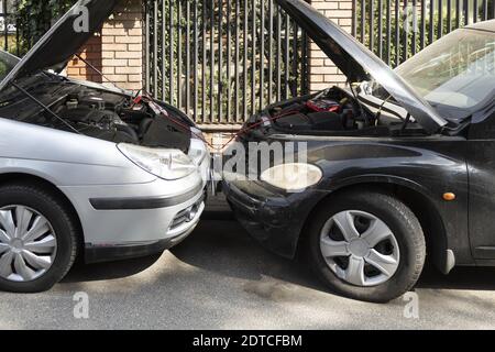 Laden der Batterie von einem anderen Fahrzeug mit Überbrückungskabeln Stockfoto