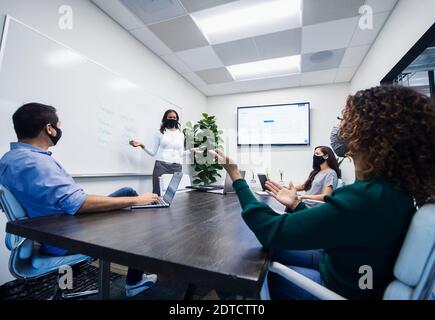 Geschäftsfrau in Gesichtsmaske geben Präsentation im Büro Stockfoto