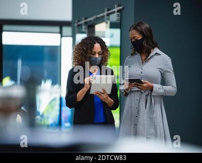 Geschäftsfrauen in Gesichtsmasken mit digitalen Tablets im Büro Stockfoto