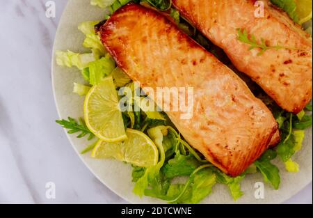 Gegrillter Lachs mit Salat auf grauem Teller. Nahaufnahme. Stockfoto
