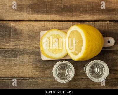 Zwei Gläser mit Tequila und Zitrone und Salz auf einem Holzhintergrund Stockfoto