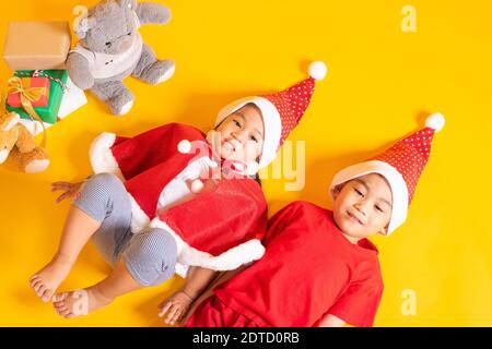 Asiatische kleine niedliche Kind Junge und Mädchen lächeln, Draufsicht auf zwei Brüder Kind in roten Weihnachtsmann hat das Konzept der Urlaub Weihnachten Weihnachtstag oder H gekleidet Stockfoto