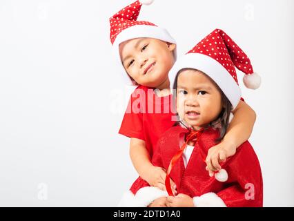 Asiatische kleine niedliche zwei Brüder Kinder junge und Mädchen lächeln, Kinder in roten Weihnachtsmann Hut umarmt zusammen Konzept der Urlaub Weihnachten Weihnachtstag gekleidet Stockfoto