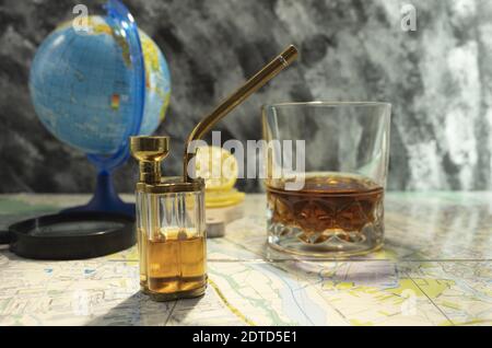 Globus mit einer Karte auf dem Tisch. Dekanter mit Cognac Whiskey auf der Karte. Punkte und Lupe auf der Karte. Stockfoto