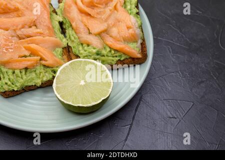 Vollkornbrot mit Avocado-Paste, Limette, Lachs auf einer Marmoroberfläche Stockfoto