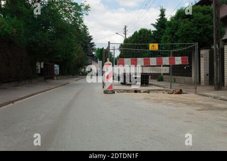 Der Graben ist auf der Straße und ist eingezäunt. Reparaturarbeiten. Die Reparatur der Kommunikationen in der Stadt Stockfoto