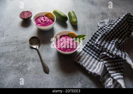 Nahaufnahme von Rote Beete Dip serviert in zwei kleinen Schüsseln zusammen mit Gemüsewürzen auf einem Hintergrund. Stockfoto