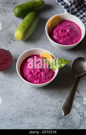 Draufsicht auf Rote Beete Dip serviert in zwei kleinen Schüsseln zusammen mit Gemüsewürzen auf einem Hintergrund. Stockfoto