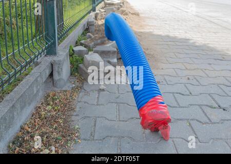 Verlegung der Kommunikation in den Wellrohren. Blaue Wellrohr liegt auf dem Boden innerhalb der Stadt Stockfoto